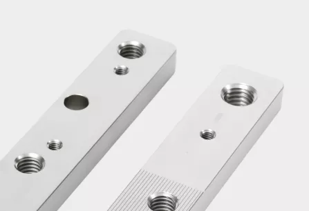 Two CNC machined aluminum bars with threaded holes and precision features