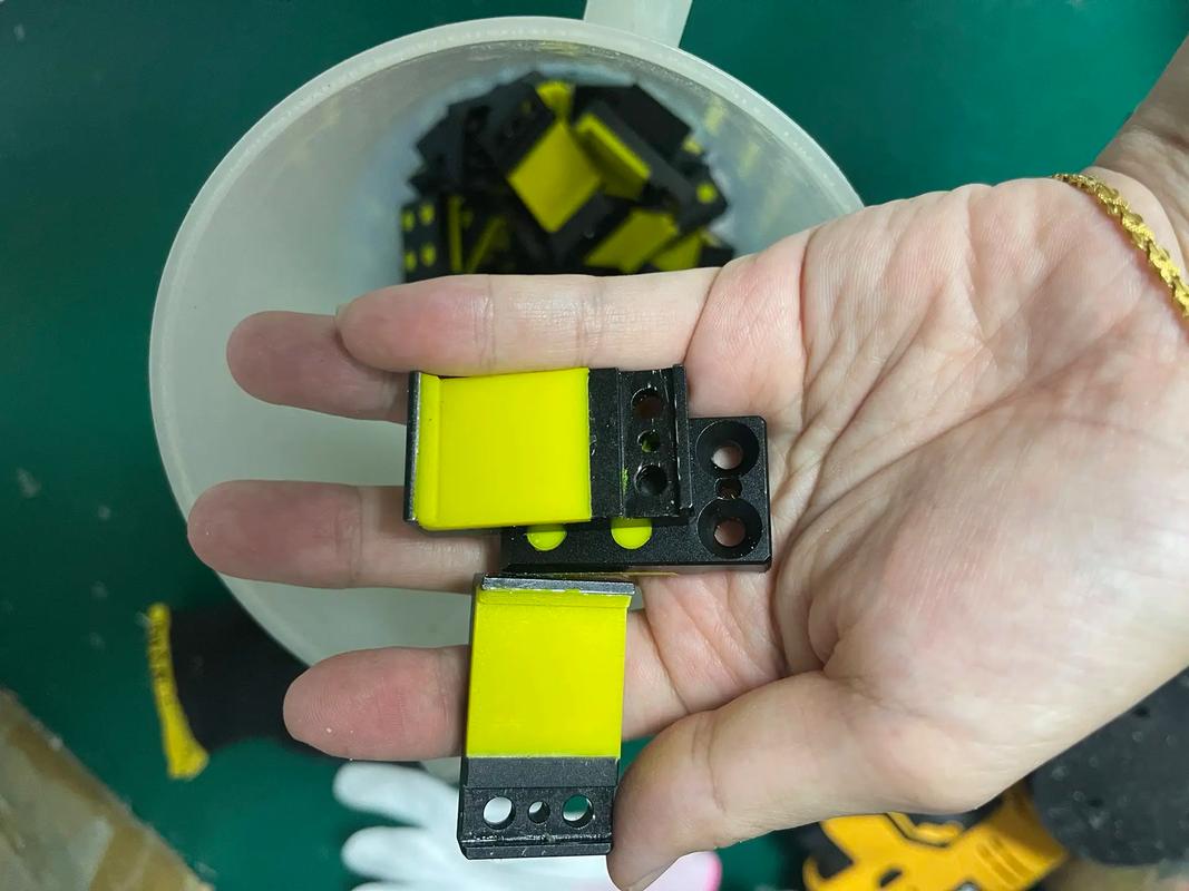 Small yellow and black two-material molded samples shown during production inspection